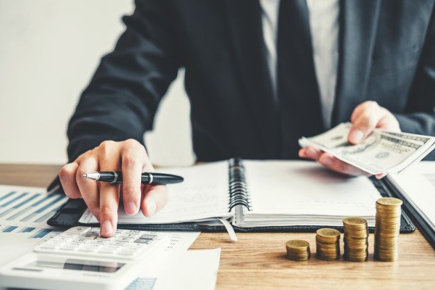 Bir kişi masada para ve hesap makinesiyle finansal hesaplama yapıyor